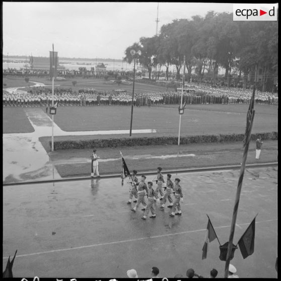 20 Plan d'ensemble, en plongée, du défilé des troupes avec le drapeau du 6e RIC, en arrière-plan les troupes rassemblées [description provisoire]