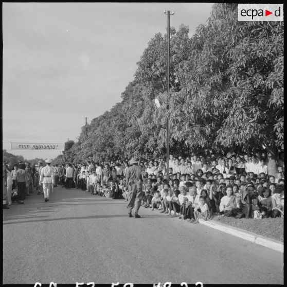 22 La foule, massée le long des trottoirs, assistant à la revue (plan d'ensemble). [description provisoire]