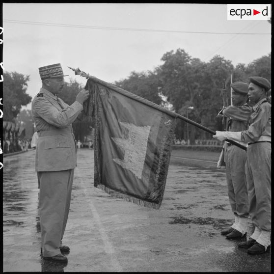 6 Plan rapproché sur le général Girot de Langlade décorant le drapeau de l'ARK de la Croix de guerre des TOE avec palme. [description provisoire]