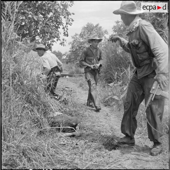 Au cours d'un accrochage, des voltigeurs fouillent un fourré où se trouve le cadavre d'un partisan du vietminh. [description provisoire]