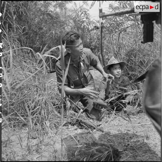 Au cours d'un accrochage avec un bataillon vietminh (TD 309), les pourvoyeurs rechargent en hâte les boites de chargeurs des fusils-mitrailleurs tandis que les voltigeurs passent au pas de course. [description provisoire]