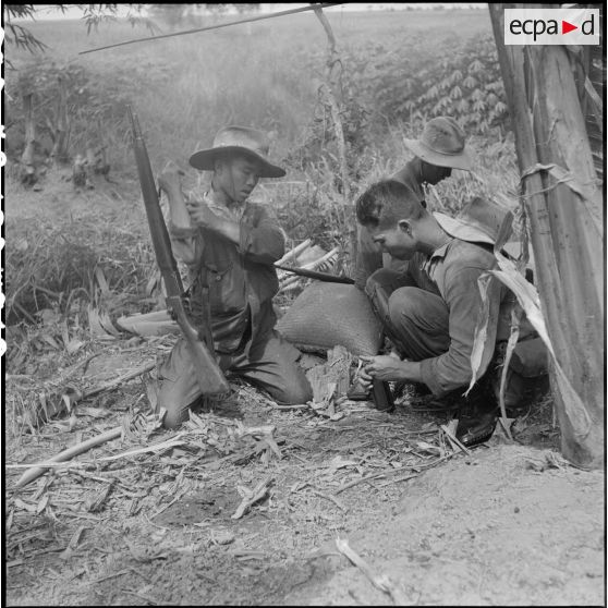Au cours d'un accrochage avec un bataillon vietminh (TD 309), les pourvoyeurs regarnissent en hâte les boites des chargeurs des fusils mitrailleurs. [description provisoire]