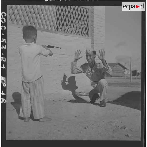 Jeu entre un soldat de la 1re compagnie du 13e bataillon vietnamien et son fils au cantonnement. [description provisoire]