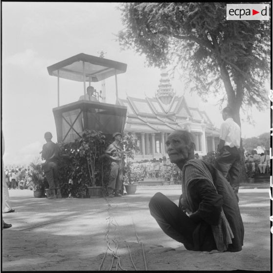 17 Vieux notable cambodgien assis par terre, en train d'écouter le discours du prince Sihanouk depuis sa tribune. [description provisoire]