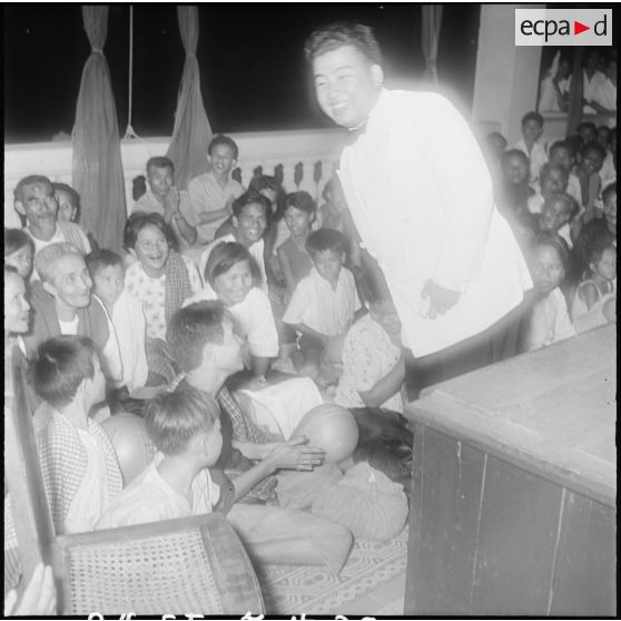 30 Plan rapproché sur le prince Norodom Sihanouk au milieu d'un groupe de Cambodgiens, de nuit. [description provisoire]