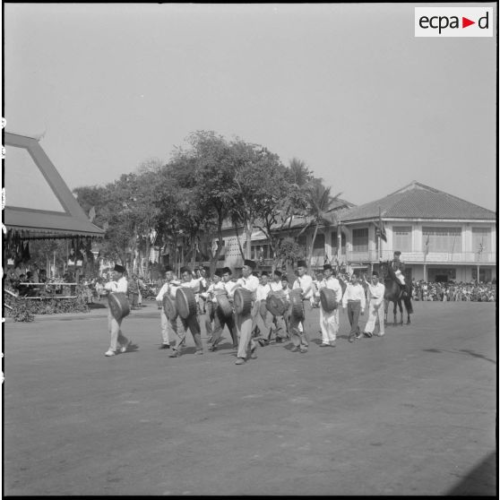 Couronnement du roi Suramarit et de la reine Kossamak du Cambodge à Phnom Penh : défilé des musiciens devant la tribune officielle. [description provisoire]