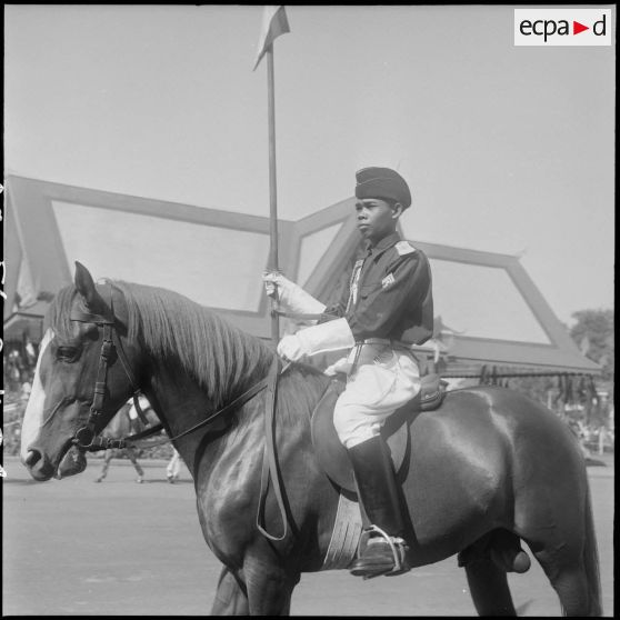 Couronnement du roi Suramarit et de la reine Kossamak du Cambodge à Phnom Penh : un garde à cheval défile devant la tribune officielle. [description provisoire]