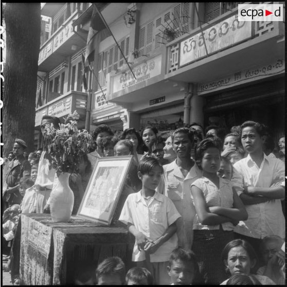 49 Plan rapproché sur la foule et un petit autel où est posé un portrait du roi et de la reine du Cambodge. [description provisoire]