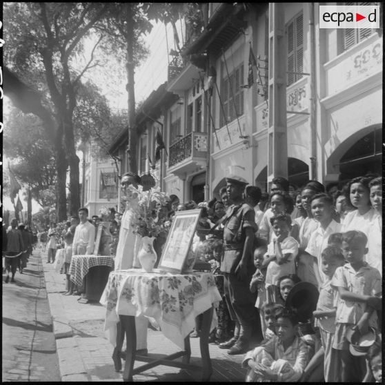 51 Plan moyen sur la foule et un petit autel où est posé un portrait du roi et de la reine du Cambodge. [description provisoire]