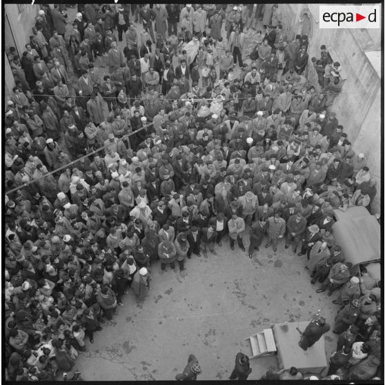 Plusieurs centaines de personnes entourent le podium où des orateurs prennent tour à tour la parole.