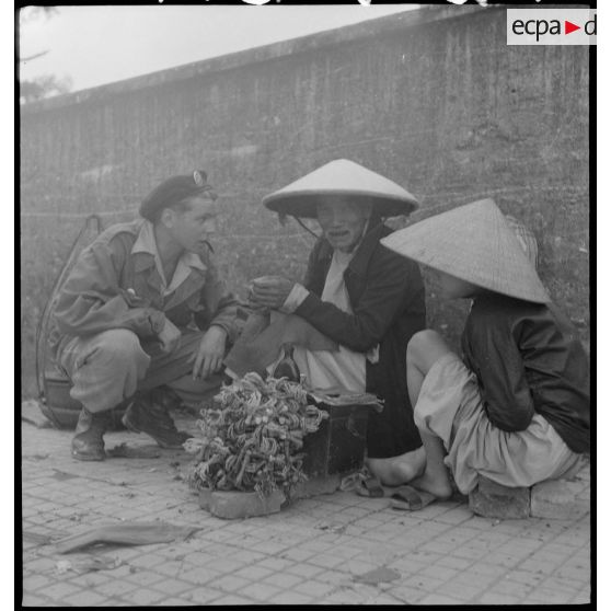 Parachutiste parlant à un marchand de rue vietnamien, dans la ville de Hué.