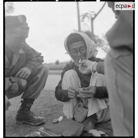 Parachutistes auprès d'un Vietnamien assis dans une rue de Hué.