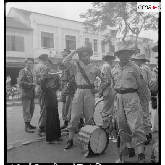 Groupe de parachutistes à proximité d'une musique militaire vietnamienne se préparant à donner un concert en ville.