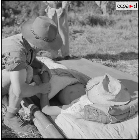 Le médecin-lieutenant Guiraud examine un chasseur laotien blessé par l'explosion d'une mine au cours de l’opération Frimaire dans la province de Xieng Khouang.