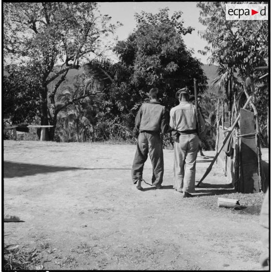 Un prisonnier laotien entravé aux pieds se déplace aux côtés d'une sentinelle, en marge de l'opération Frimaire dans la province de Xieng Khouang.