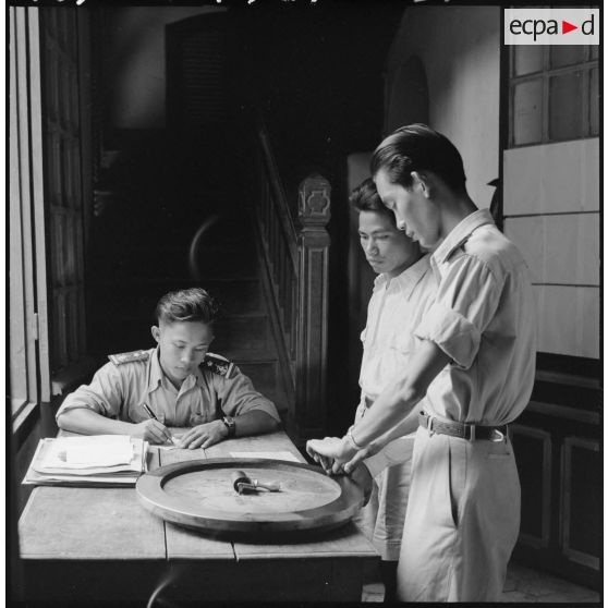 Un inspecteur de la police nationale laotienne établit l'identité judiciaire d'un suspect appréhendé tandis qu'un sous-inspecteur relève ses empreintes digitales.