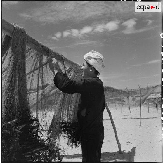 Un pêcheur étend ses filets au retour de la pêche sur la plage à Cu Lao.