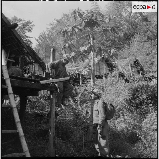 Des chasseurs du 2e bataillon de chasseurs laotiens (2e BCL) inspectent une paillote d'un village Kha dans la région de Ban The.