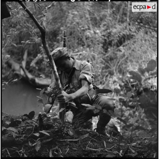 Un chasseur du 2e bataillon de chasseurs laotiens (2e BCL) atteint le sommet de la rive après l'avoir escaladée.