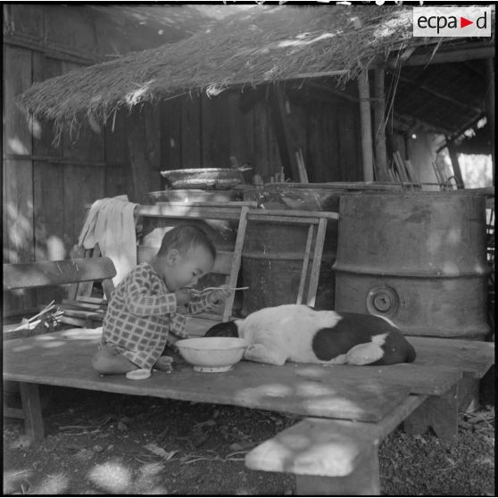 Enfant lao mangeant une soupe à l'extérieur d'une maison, à Savannakhet.