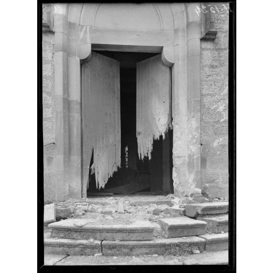 Hénaménil (Meurthe-et-Moselle). Entrée de l'église. Porte déchiquetée par les balles. [légende d'origine]