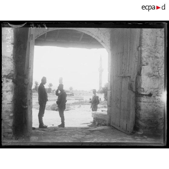 [Deux soldats discutent sous un espace couvert en avant de l'entrée d'un édifice.]