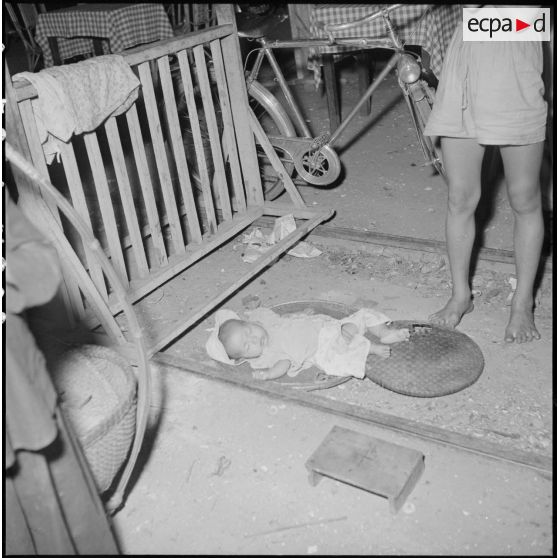 Bébé dormant au sol dans une rue de Saigon.