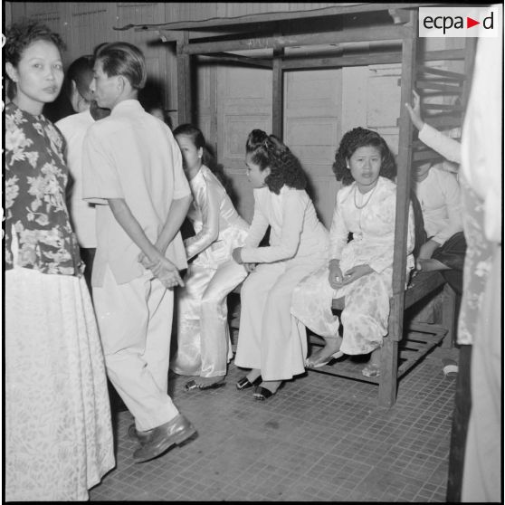 La vie nocturne à Saigon : des femmes en tenue traditionnelle (ao dai) dans la rue.