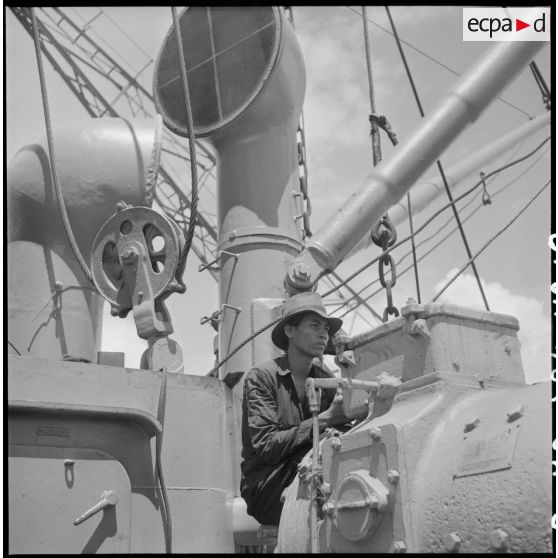 Contrôle d'un treuil par un Vietnamien à bord d'un navire au cours du déchargement de marchandises au port de Saigon.