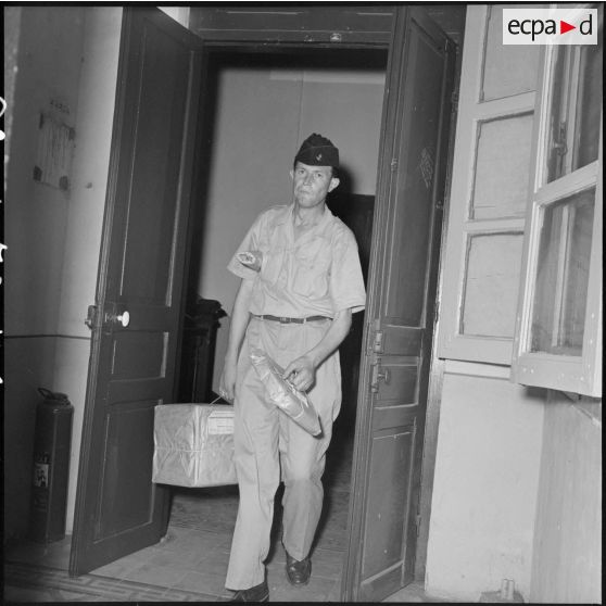 Le caporal-chef Mariteau arrive dans les locaux de la section ciné-photo du Service presse information chargé de colis.