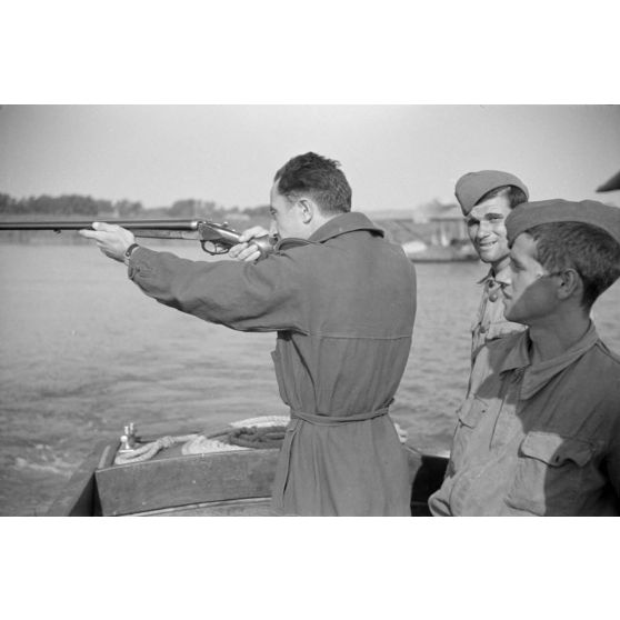 Depuis une embarcation, un officier roumain du Grupul 9 tire au fusil de chasse.