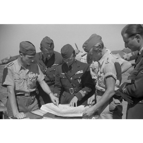 Dirigeant un briefing carte à l'appui, le capitaine Av.Gheorghe Iliescu, commandant de l'escadrille 52, en présence du sous-lieutenant Av. Lucaci Mihai, de la 52e escadrille et de pilotes allemands du Jagdgeschwader 4 (JG4).