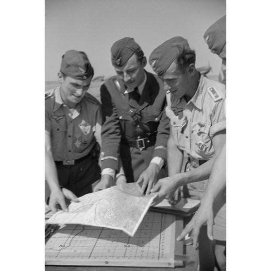 Dirigeant un briefing carte à l'appui, le capitaine Av.Gheorghe Iliescu, commandant de l'escadrille 52, en présence du sous-lieutenant Av. Lucaci Mihai, de la 52e escadrille et de pilotes allemands du Jagdgeschwader 4 (JG4).