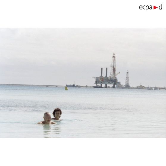 Lors d'un moment de détente pendant la visite de membres du gouvernement et d'élus du territoire polynésien sur l'atoll de Moruroa, baignade de Gaston Flosse, président de la Polynésie française, dans les eaux du lagon. En arrière-plan, une barge.