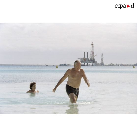 Lors d'un moment de détente pendant la visite de membres du gouvernement et d'élus du territoire polynésien sur l'atoll de Moruroa, baignade de Gaston Flosse, président de la Polynésie française, dans les eaux du lagon. En arrière-plan, une barge.