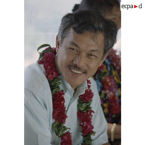 Portrait du maire adjoint de Papeete avec un collier de fleurs de tiaré lors de la visite d'une délégation de membres du gouvernement et d'élus du territoire polynésien sur l'atoll de Moruroa.