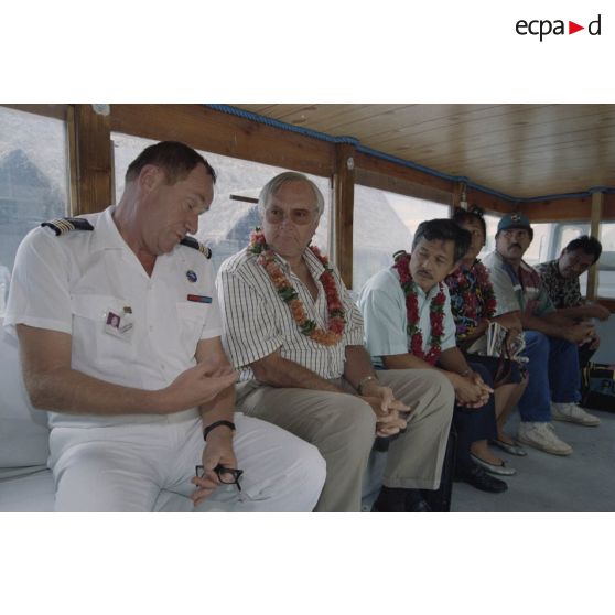 Gaston Flosse, président de la Polynésie française, est accueilli par le colonel Delcourt, commandant du site (COMSITE), lors de la visite de membres du gouvernement et d'élus du territoire polynésien sur l'atoll de Moruroa, dont le maire adjoint de Papeete. Déplacement à bord d'un truck bus.