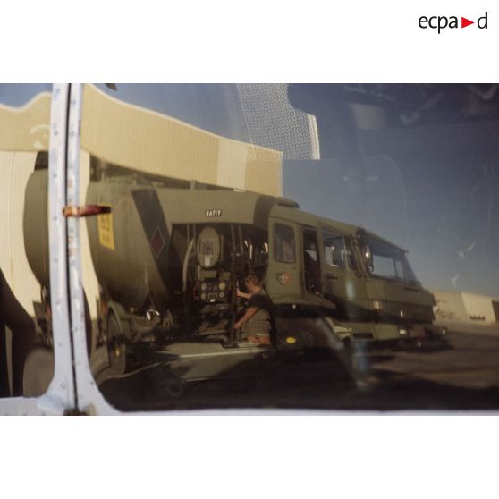 Reflet d'un camion-citerne du service des essences des armées (SEA) sur la cabine d'un hélicoptère Super-Puma de l’escadron de transport d’hélicoptères d’outre-mer (ETOM) 82 stationné sur l'aéroport de l'atoll de Moruroa.