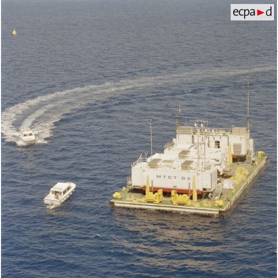 Vue aérienne d'une barge d’enregistrement et de mesure (BEM) et de vedettes du Commissariat à l’énergie atomique (CEA) dans le lagon de l'atoll de Moruroa.