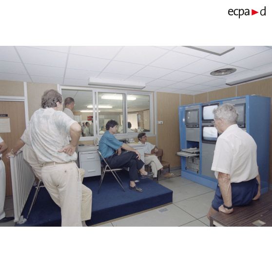 Portrait de personnel civil devant des moniteurs dans la salle de commandement du groupement opérationnel des essais nucléaires (GOEN) pendant le tir nucléaire Aepytos du 27 octobre 1995.