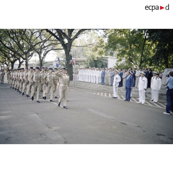 Défilé des troupes devant Charles Hernu, ministre de la Défense, lors d'une cérémonie militaire à Papeete, accompagné de Paul Noirot-Cosson, haut-commissaire de Polynésie française, du contre-amiral Jacques Choupin, commandant le Centre d'expérimentations du Pacifique (CEP), et du contre-amiral René Hugues, chef du cabinet militaire.