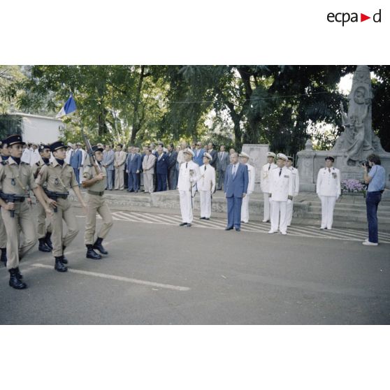 Défilé des troupes devant Charles Hernu, ministre de la Défense, lors d'une cérémonie militaire à Papeete, accompagné de Paul Noirot-Cosson, haut-commissaire de Polynésie française, du contre-amiral Jacques Choupin, commandant le Centre d'expérimentations du Pacifique (CEP), et du contre-amiral René Hugues, chef du cabinet militaire.