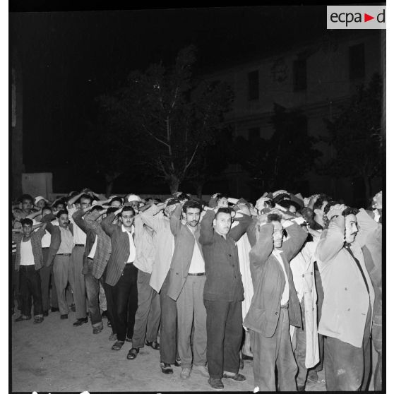 Lors d'une opération de bouclage de la casbah d'Alger par le 3e régiment de parachutistes coloniaux (3e RPC), des hommes suspects sont rassemblés les mains sur la tête.
