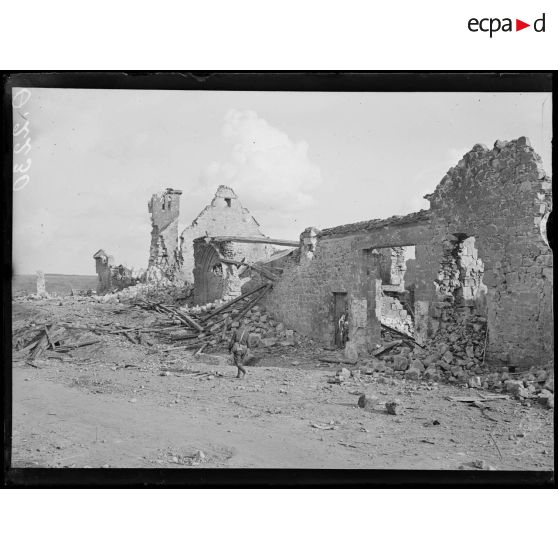 [Un soldat passe à travers un village en ruines.]