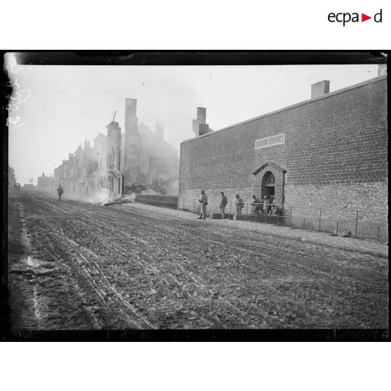 [Des soldats sortent de la maison d'arrêt, dans la ville de Vouziers, à côté de laquelle une maison est en feu.]