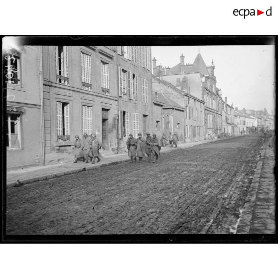 [Un groupe de soldats passe à travers le centre ville de Vouziers en ruines.]