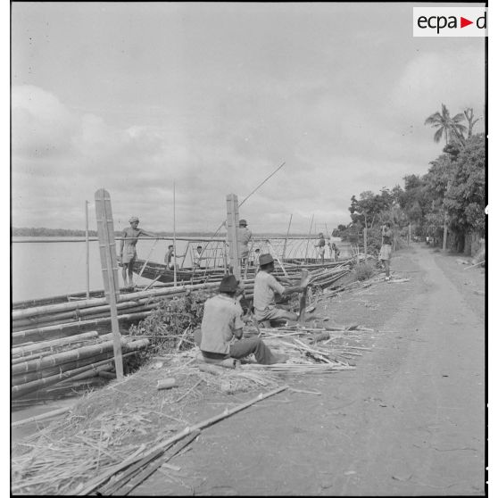 Fabrication d'un toit de bambous sur pirogue au bord du Mékong.