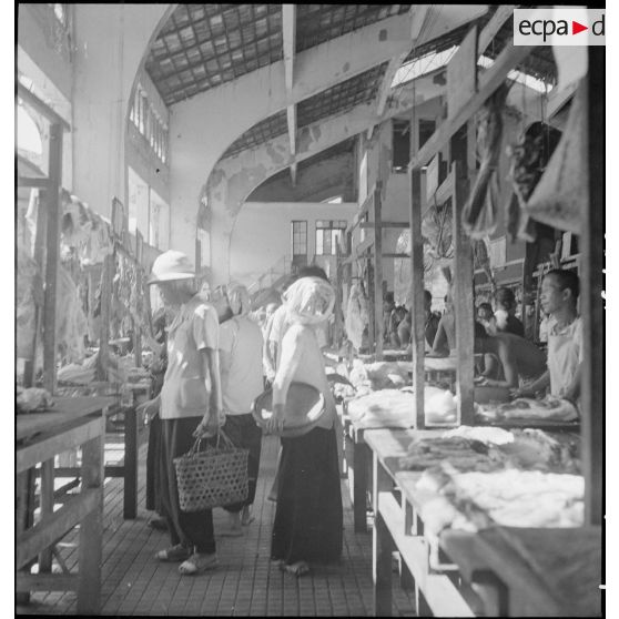 Acheteurs circulant entre les étals du marché couvert de Saigon.