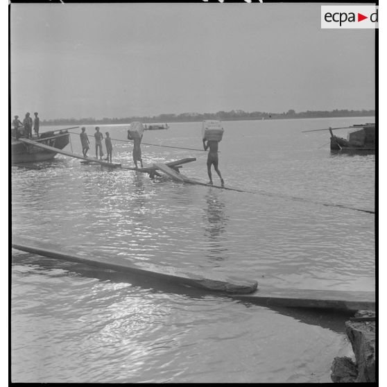 Chargement de caoutchouc sur des jonques sur le Mékong.