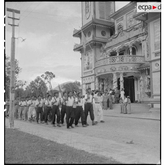 Défilé d'hommes de l'armée caodaïste devant le temple de Tay Ninh.